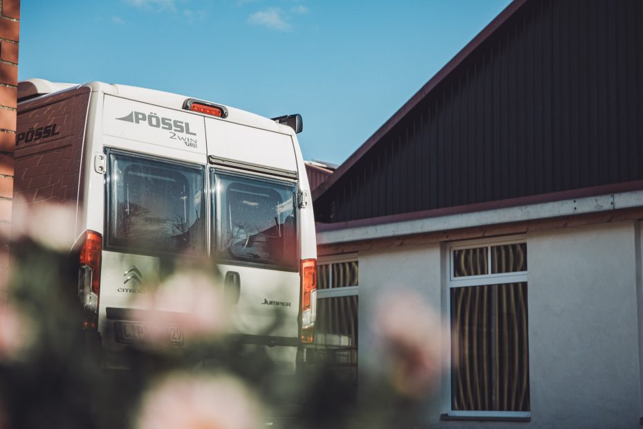 Rückansicht eines weißen Citroën-Pössl-Campers auf dem Hof Massmann in Osnabrück – ein idyllischer Stellplatz für Landvergnügen-Reisende, eingebettet zwischen Scheunen und Fachwerkhäusern.