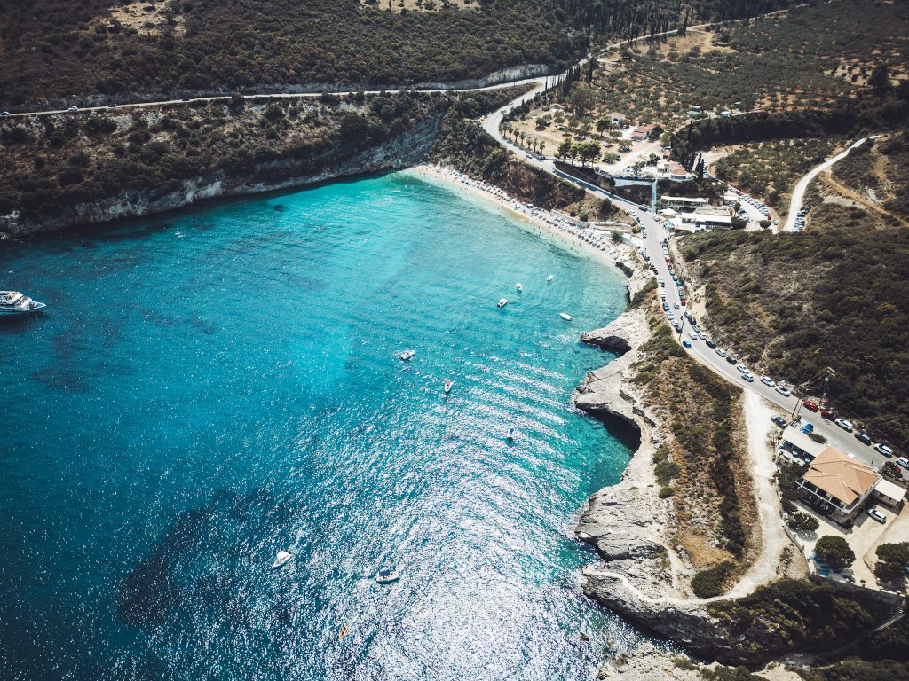 Blick aus der Luft auf die geschützte Bucht Makris Gialos auf Zakynthos mit klarem Wasser, Booten und der umliegenden Berglandschaft