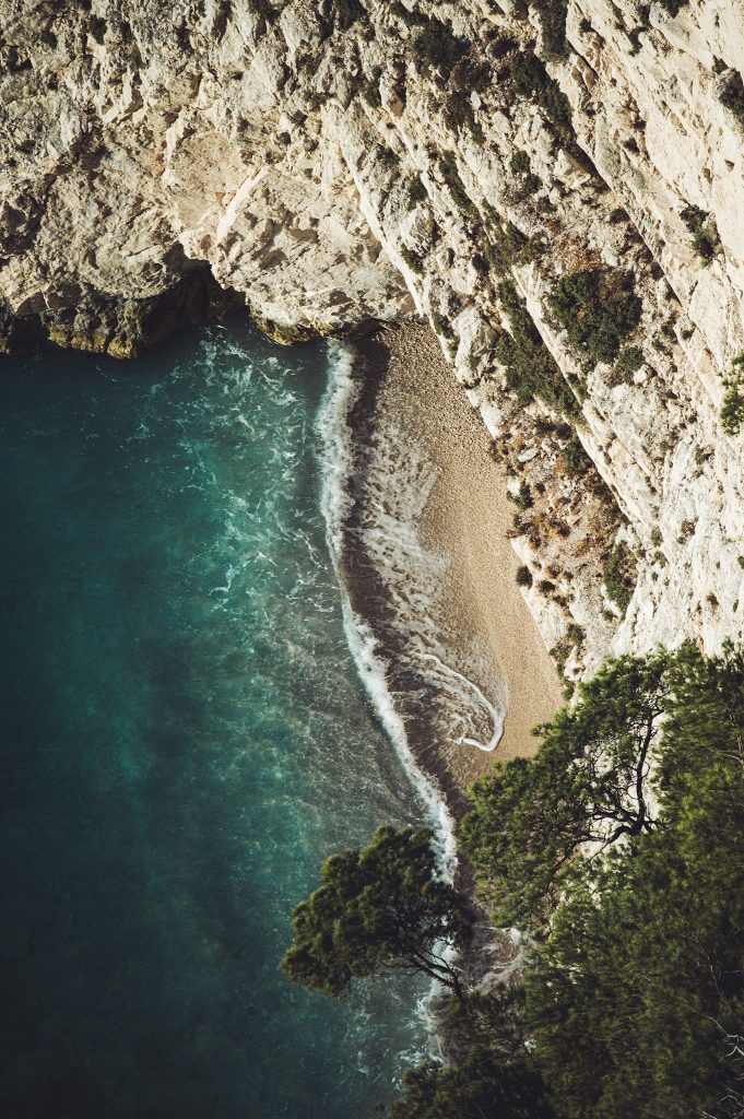 Versteckter, von Klippen eingerahmter Strand an der Steilküste von Zakynthos, aufgenommen von oben.