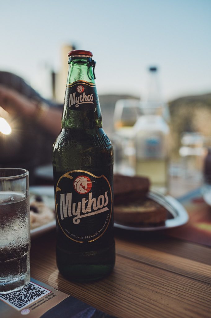Mythos-Bierflasche bei entspannter Atmosphäre während des Abendessens in der Sunset Michali's Taverna auf Zakynthos.