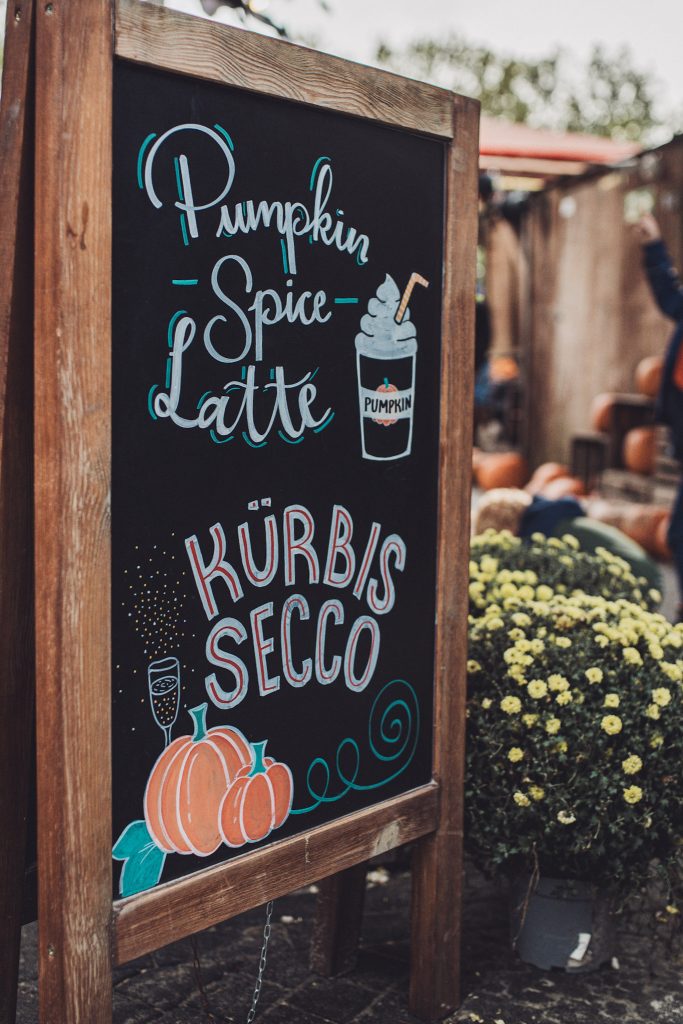Tafel mit Werbung für Pumpkin Spice Latte und Kürbis Secco auf dem Kürbisfest in Deutschland
