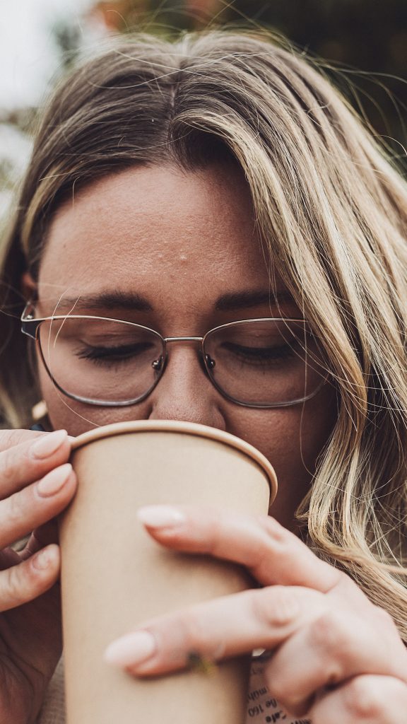 Nahaufnahme einer Frau mit Brille, die genüsslich aus einem Kaffeebecher trinkt auf dem Kürbisfest in Deutschland