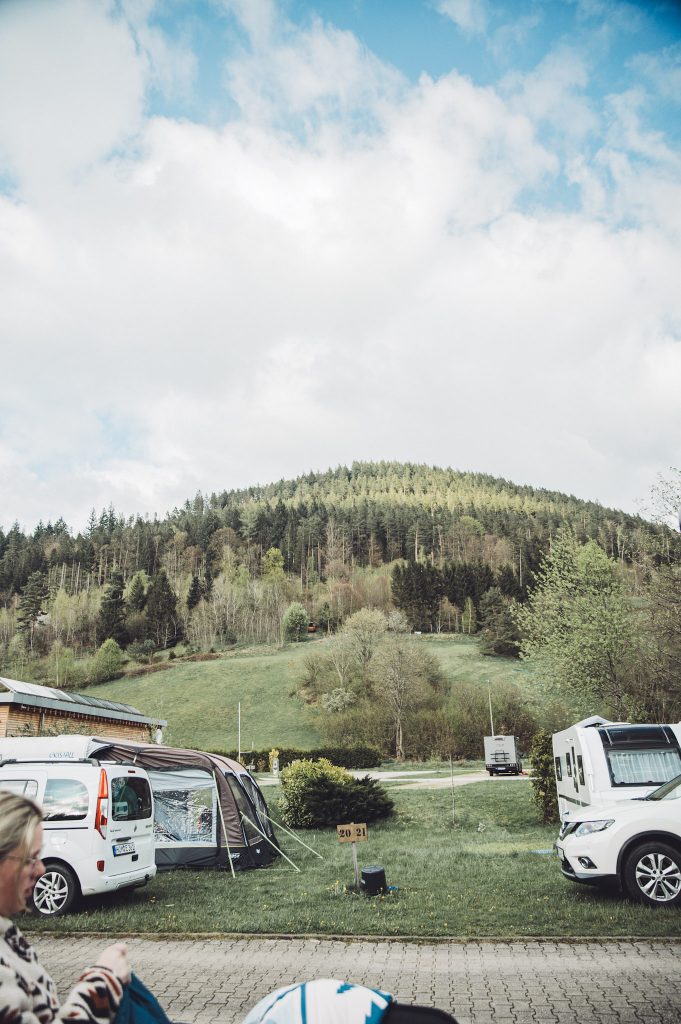 Stellplatz mit Blick auf bewaldeten Hang und offene Wiese im Natur-Camp Tannenfels im Schwarzwald