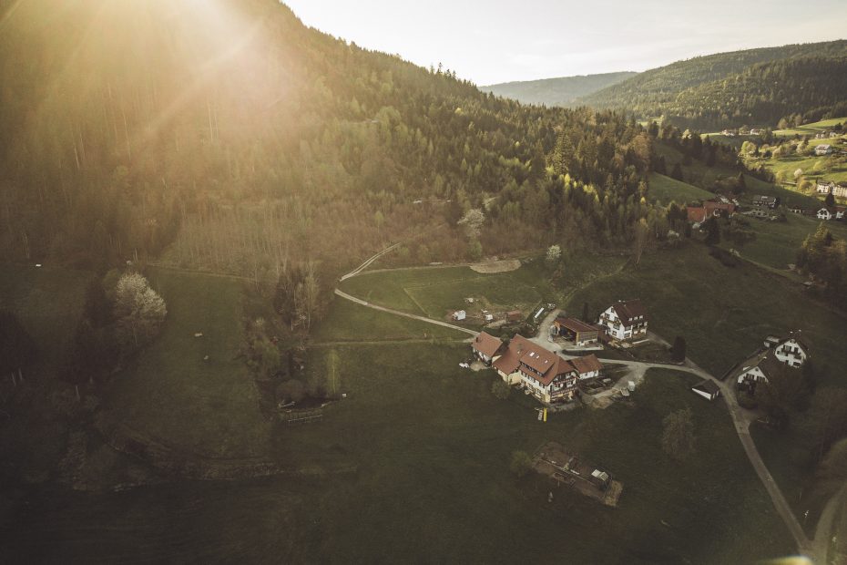 Sonnenuntergang über einem idyllischen Bauernhof im Schwarzwald, umgeben von grünen Hügeln und Wäldern, aufgenommen während unserer Camper-Auszeit.