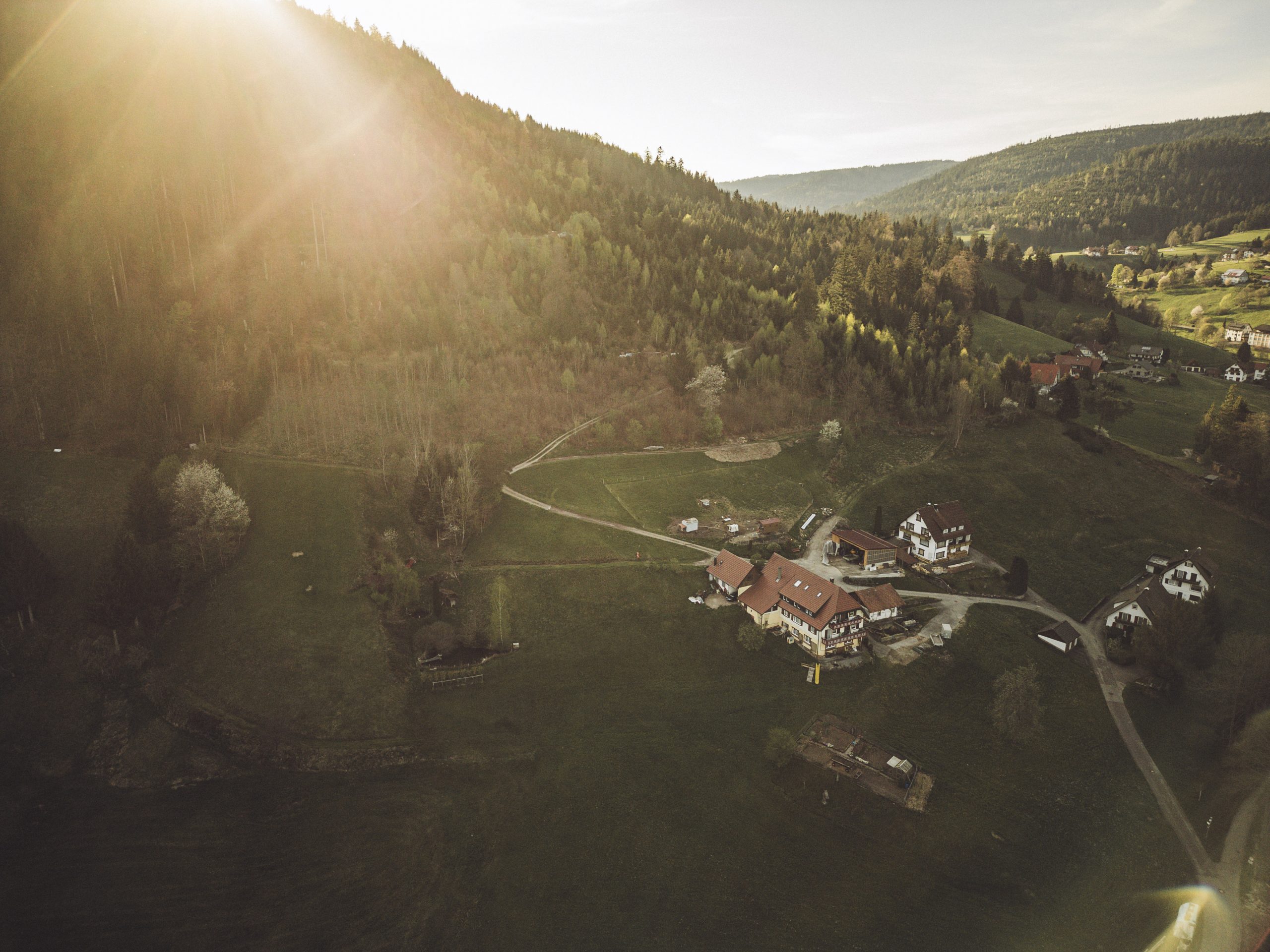 Sonnenuntergang über einem idyllischen Bauernhof im Schwarzwald, umgeben von grünen Hügeln und Wäldern, aufgenommen während unserer Camper-Auszeit.
