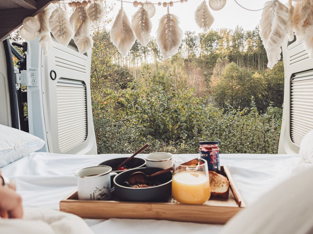 Frühstückstablett im Camper mit Waldblick durch die offenen Hecktüren