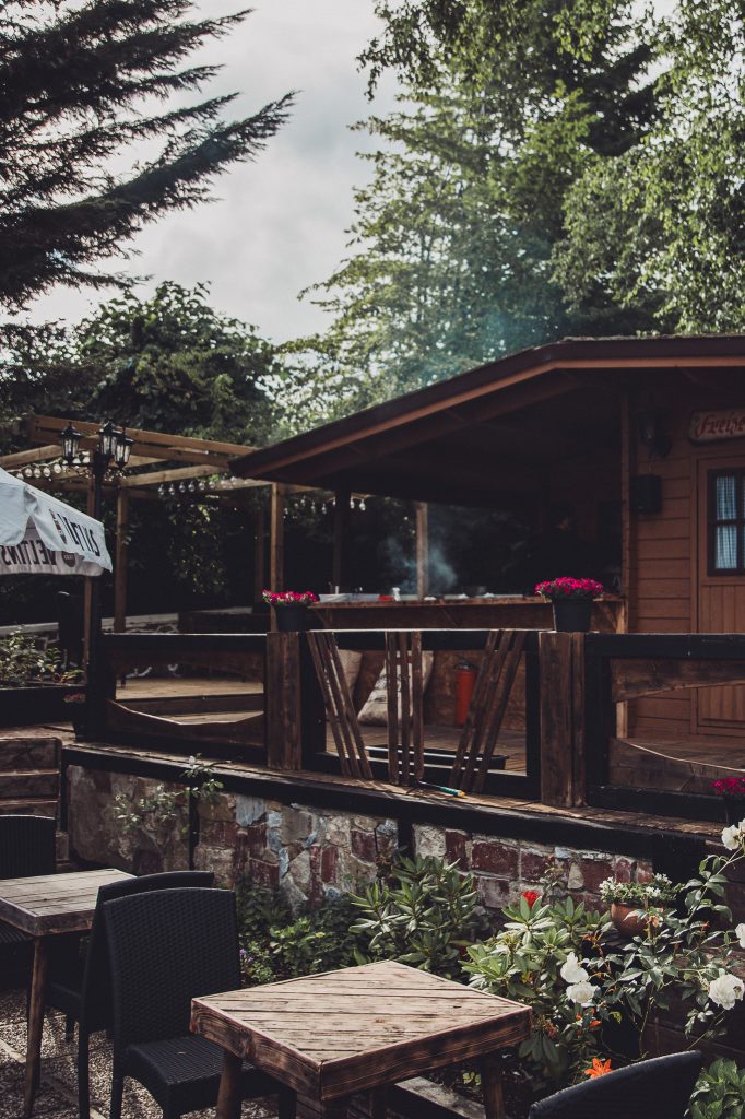Holzhütte mit Grillstation im Garten des Café Mona & Lisa, umgeben von Bäumen und Blumen