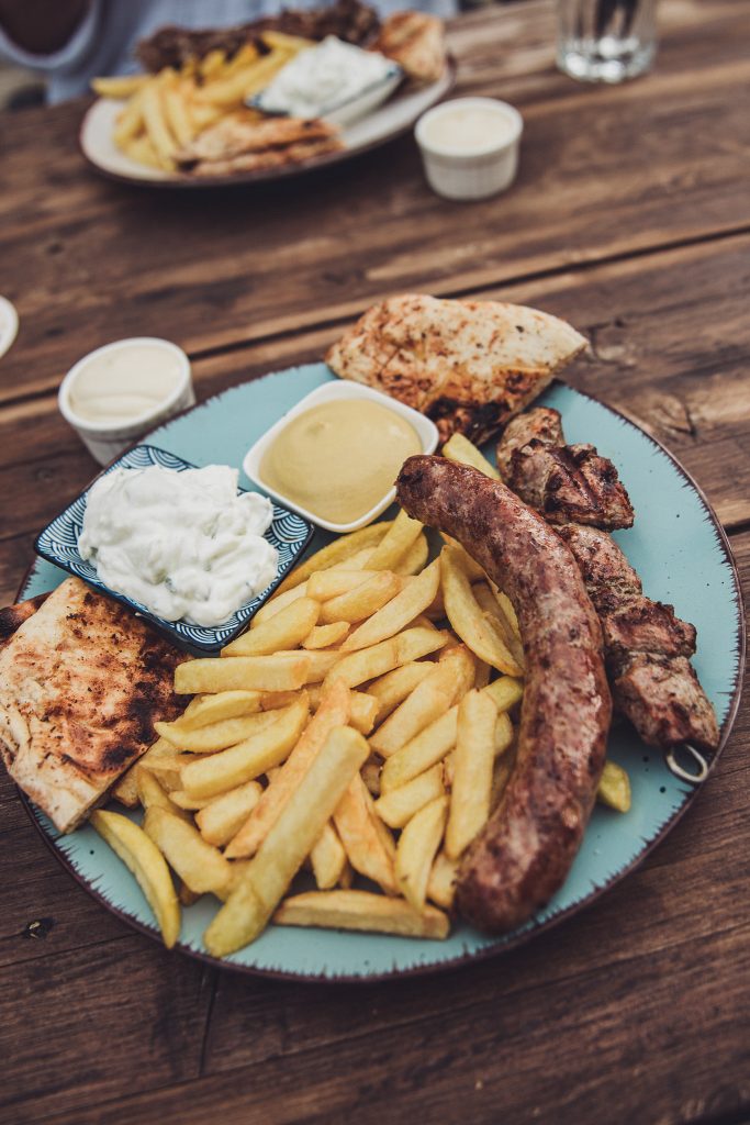 Nahaufnahme eines Grilltellers mit Bauernwurst, Pommes, Zaziki und Pita-Brot im Café Mona & Lisa