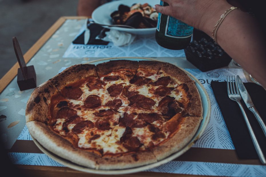 Salami-Pizza im Vordergrund, im Hintergrund ein Teller mit Meeresfrüchten