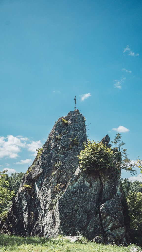 Bielsteinfelsen mit Gipfelkreuz im Wildpark Warstein unter blauem Himmel.