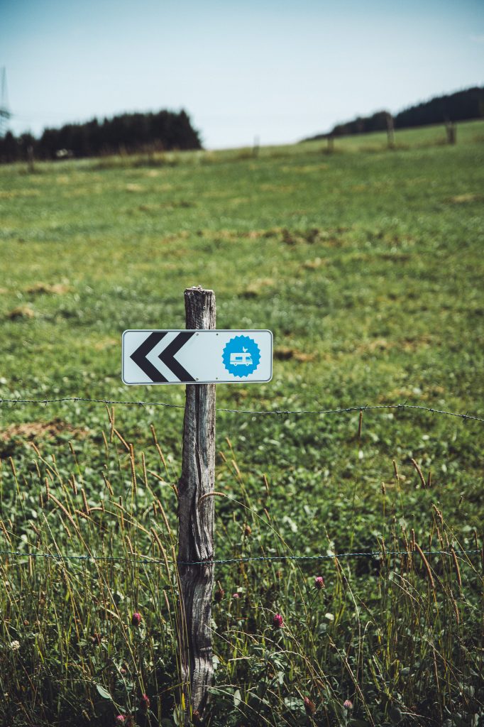 Holzpfahl mit Wegweiser zum Landvergnügen-Stellplatz