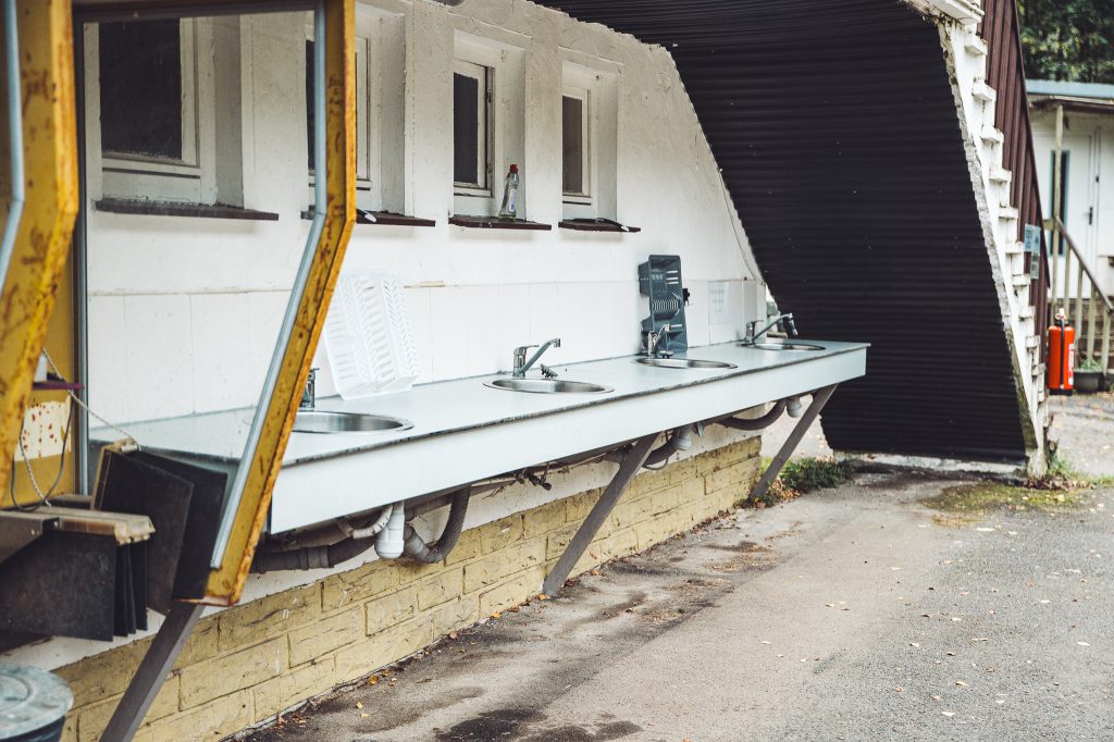 Reihe von Außenspülbecken mit Wasserhähnen am Campingplatz Niemetal.