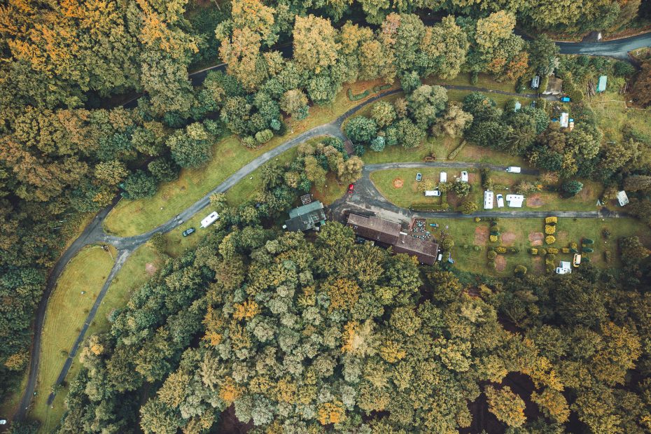 Drohnenaufnahme des Campingplatzes Niemetal mit Parzellen und Gebäuden, umgeben von Wald.