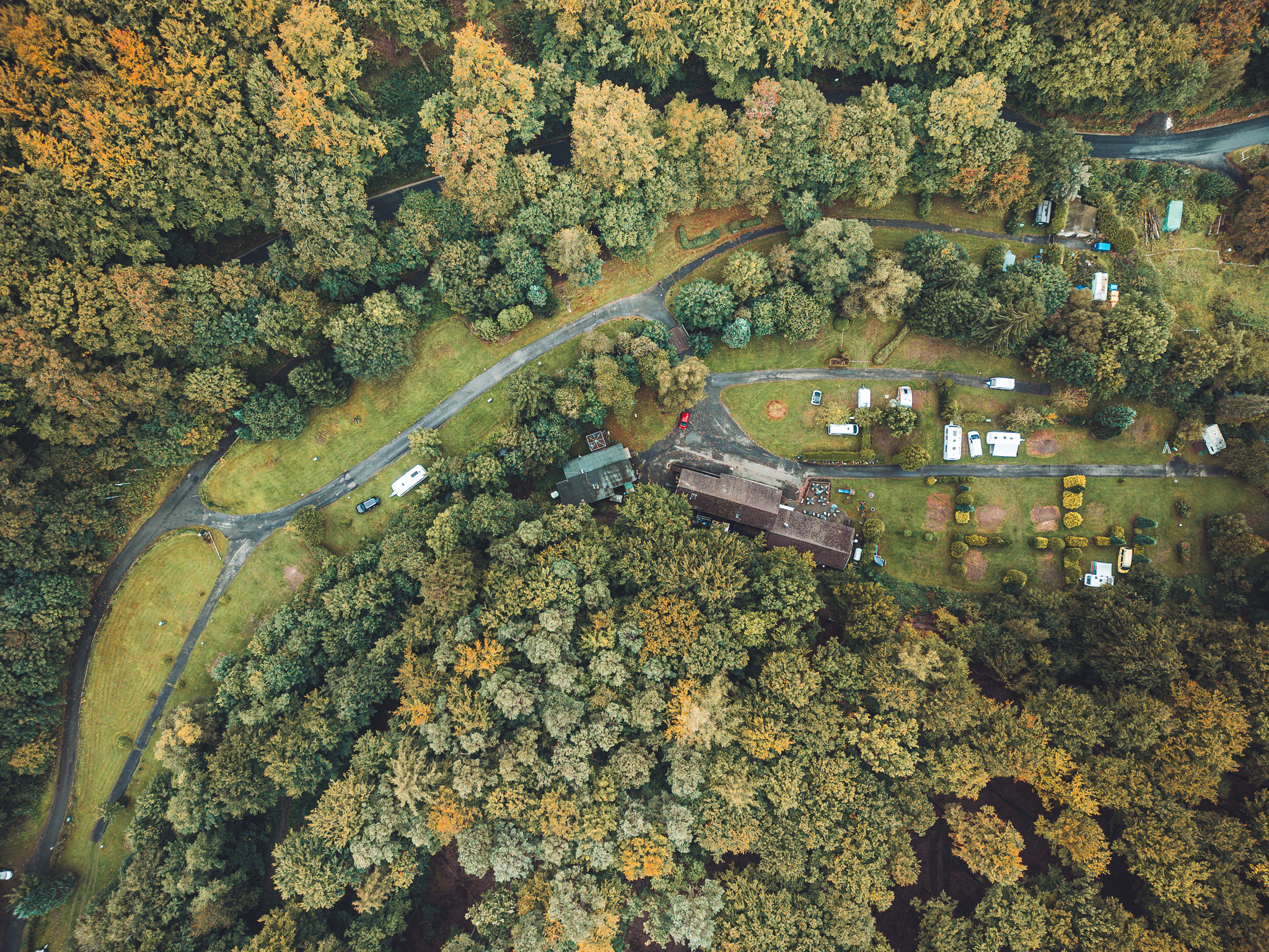 Drohnenaufnahme des Campingplatzes Niemetal mit Parzellen und Gebäuden, umgeben von Wald.