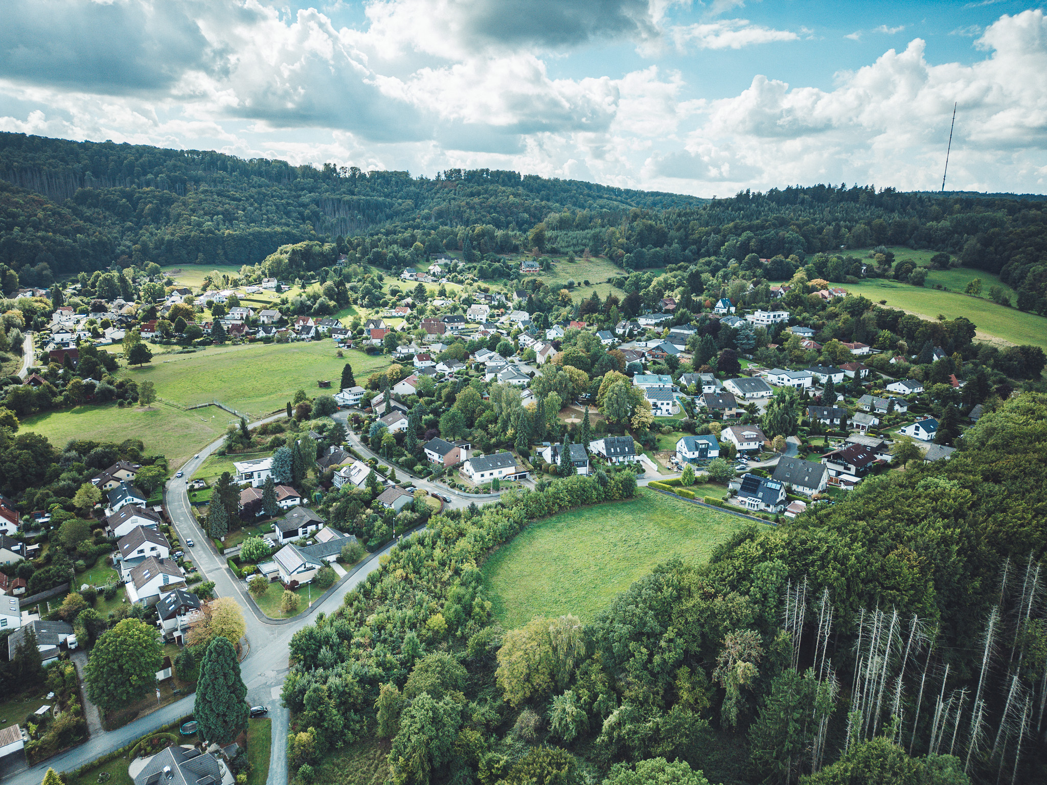 Drohnenaufnahme von Heiligenkirchen mit Wiesen, Häusern und umliegendem Wald