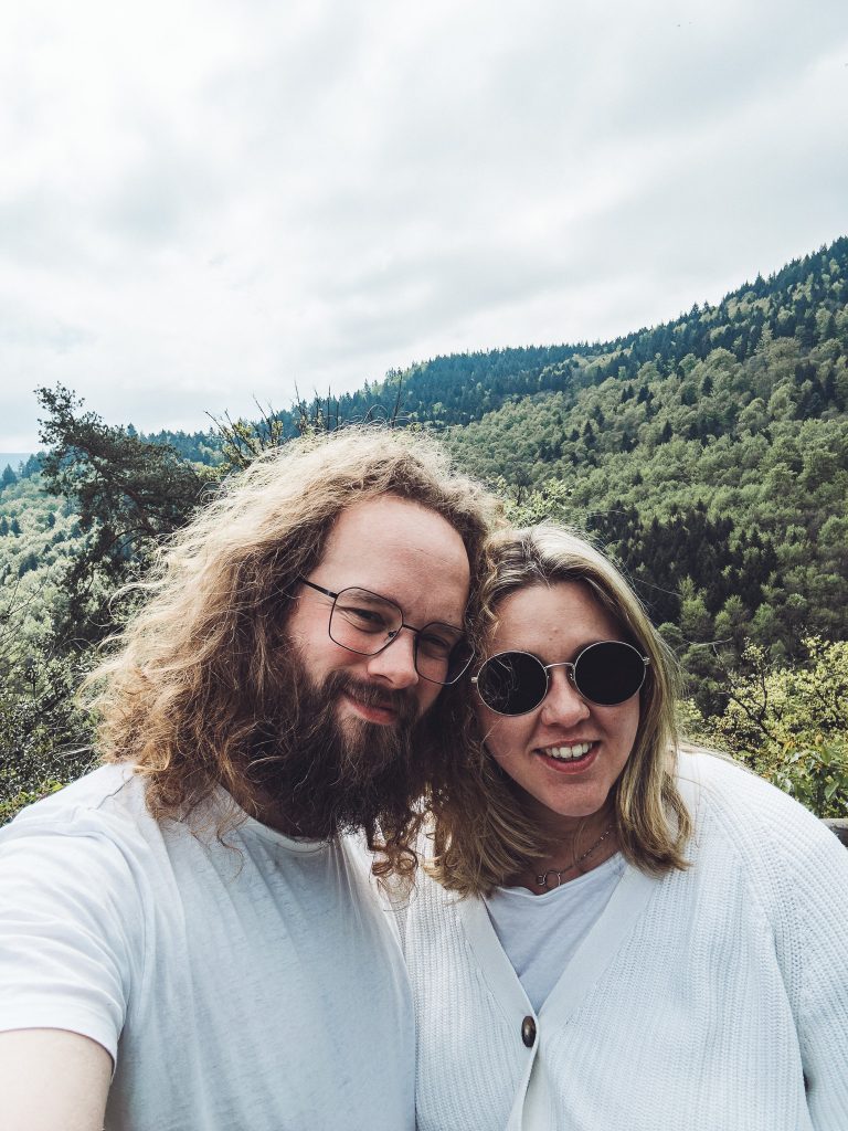 Selfie von zwei Personen vor bewaldeten Hügeln im Schwarzwald