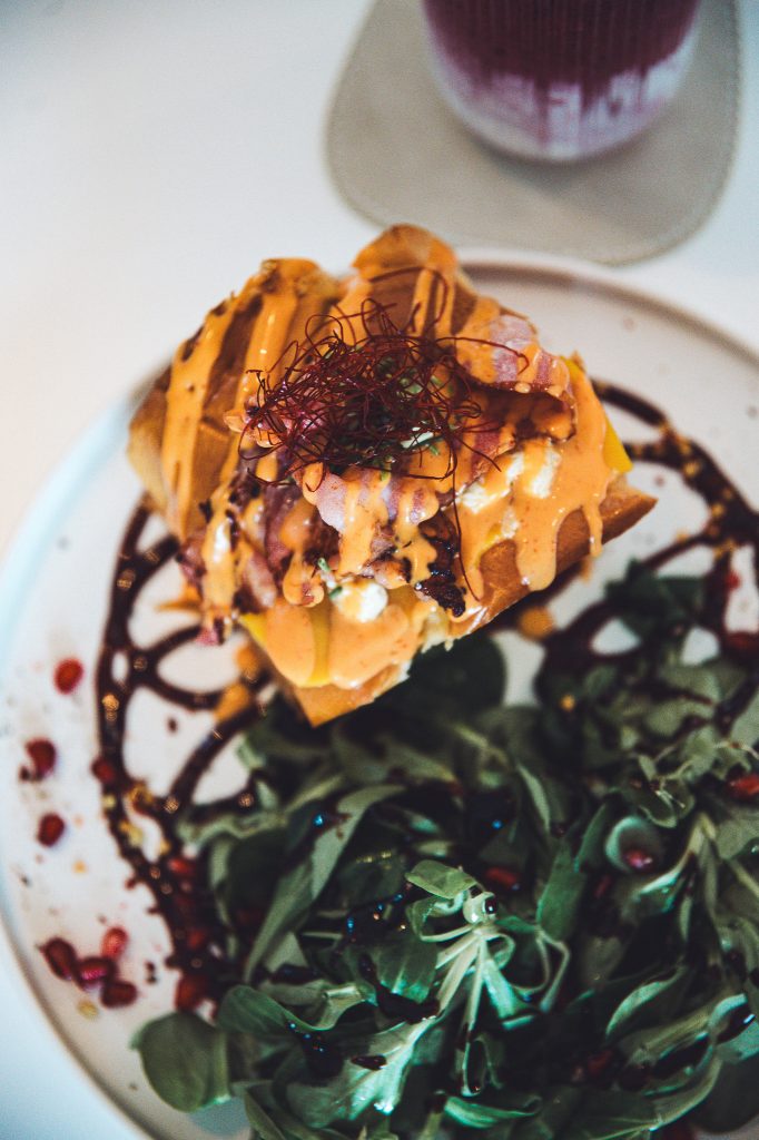 Egg-Drop-Sandwich mit Bacon, Sauce und Salat, aus der Vogelperspektive aufgenommen im Betty’s Café Wittlich.