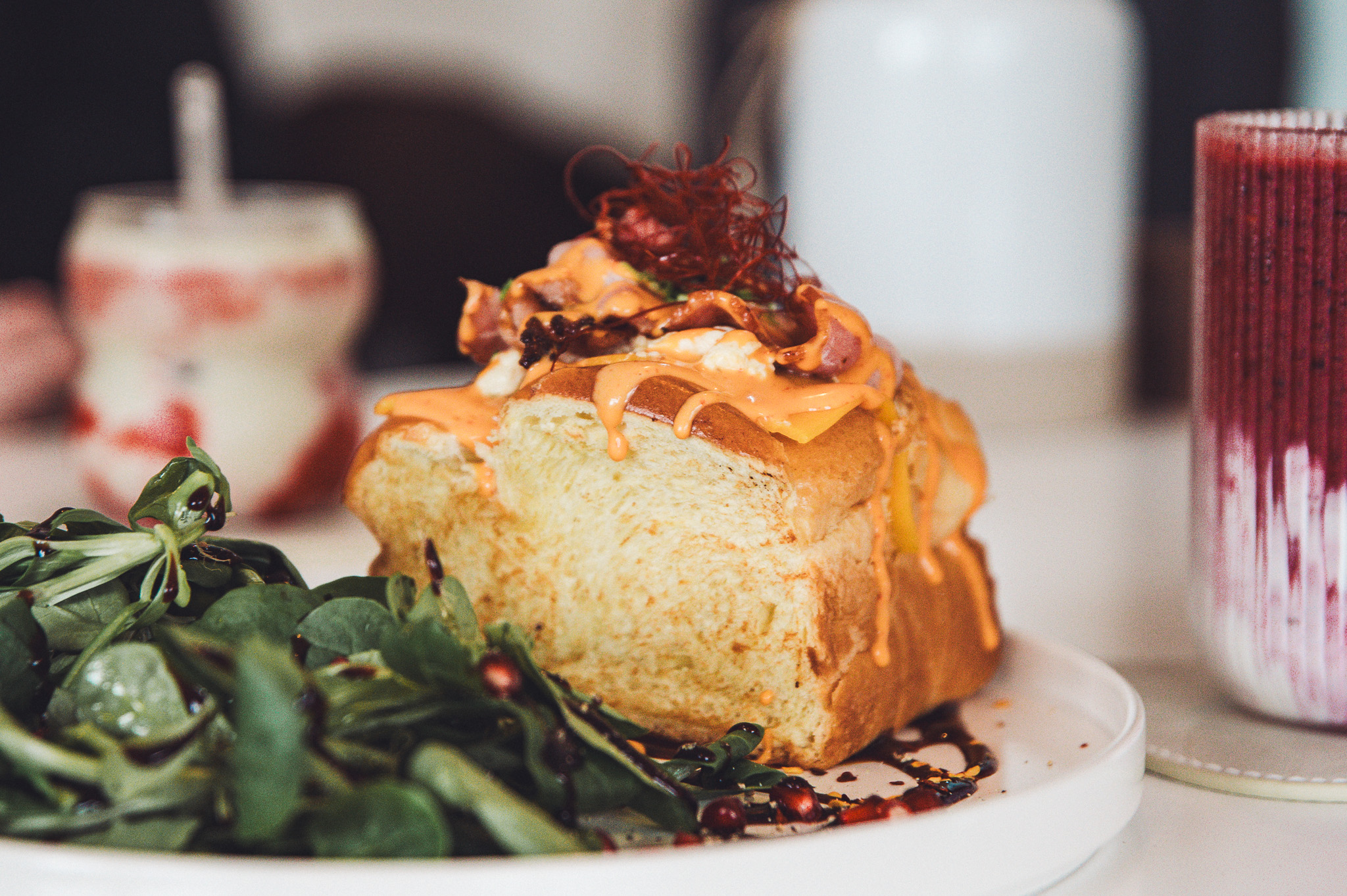 Egg-Drop-Sandwich mit Bacon und frischem Salat im Betty’s Café Wittlich, serviert auf einem weißen Teller.
