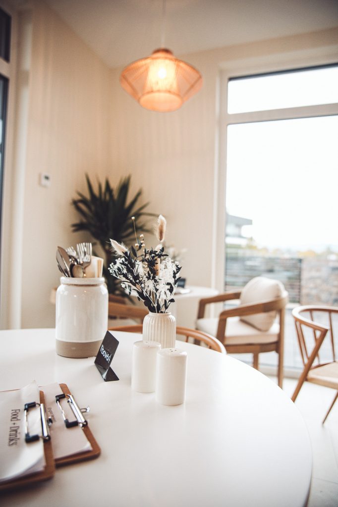 Heller Tisch mit Trockenblumen, Geschirr und Holzstühlen im modernen Interior des Betty’s Café Wittlich.