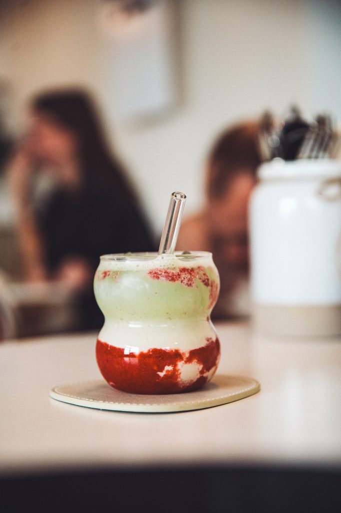 Matcha-Erdbeer-Drink im Betty’s Café Wittlich mit grün-weißen und roten Schichten in einem Glas mit Glastrinkhalm.