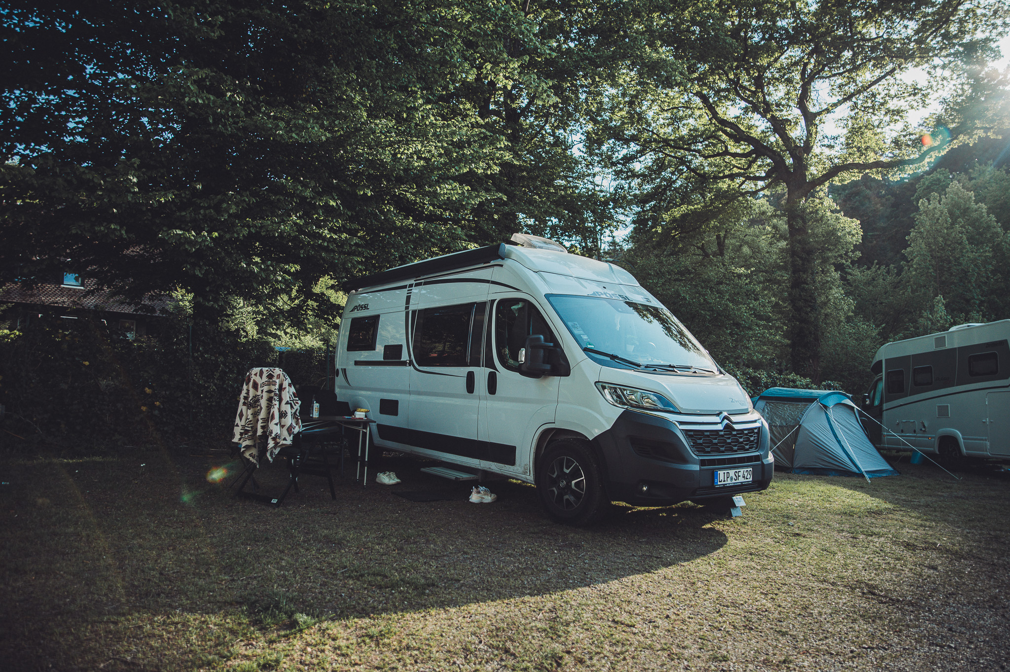 Camper auf grünem Stellplatz unter Bäumen im Camping Möslepark Freiburg