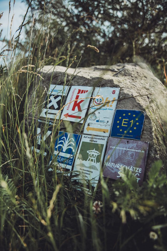 Wanderzeichen und Wegmarkierungen auf einem Stein am Velmerstot im Eggegebirge