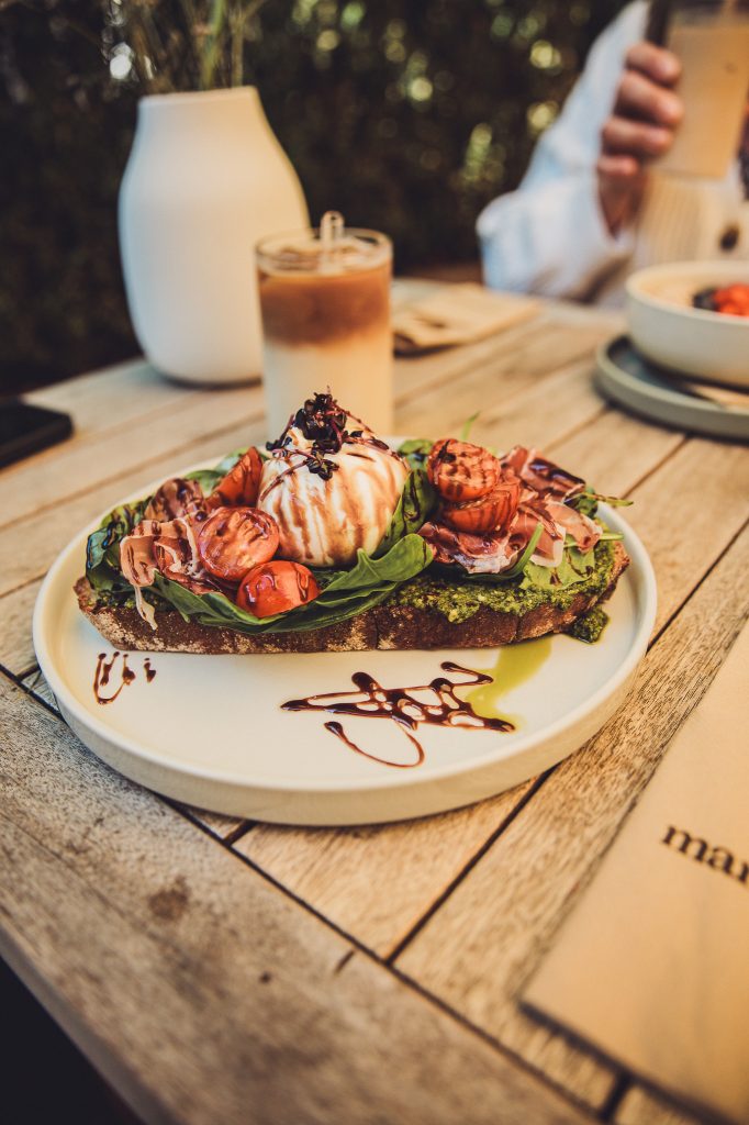 Frühstückstisch mit Burrata-Brot, Acai-Bowl und Iced Latte im Café Marmell Freiburg.