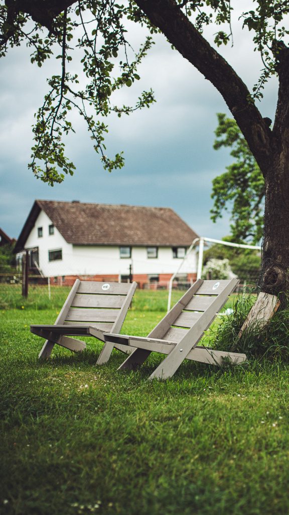 Zwei Holzliegestühle unter einem Obstbaum auf einer Wiese neben Kochs Hof in Hessen