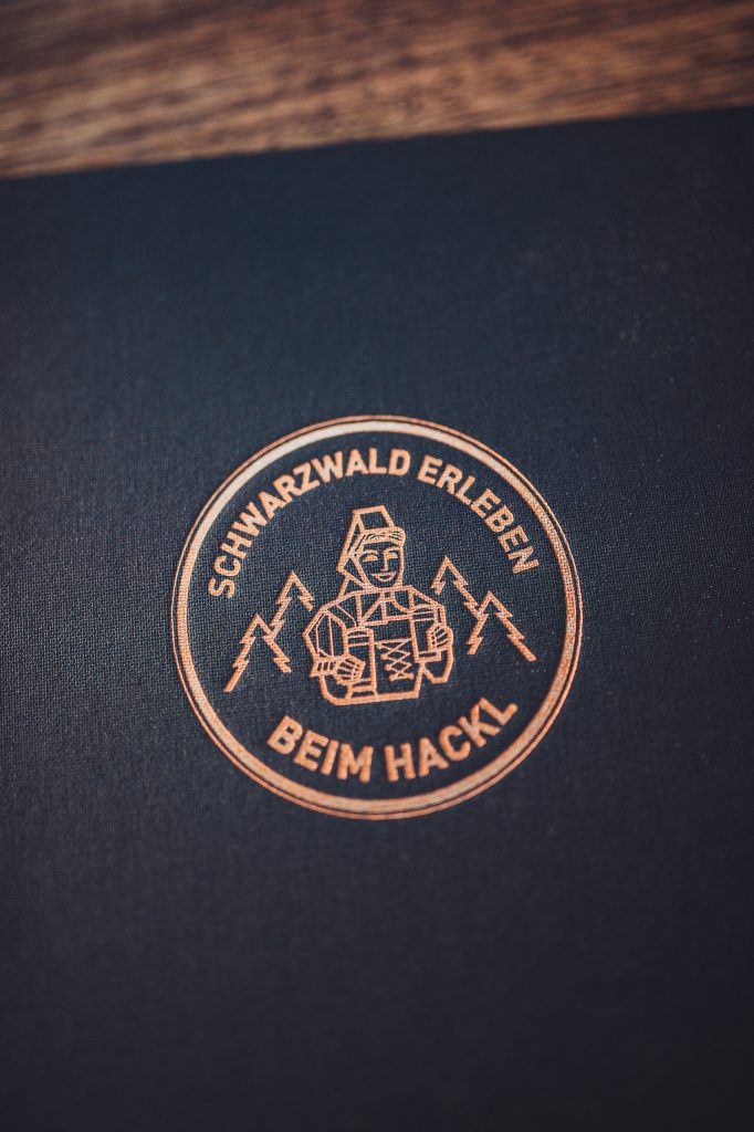 Logo des Restaurants Schwarzwald Erleben Beim Hackl auf dunklem Untergrund