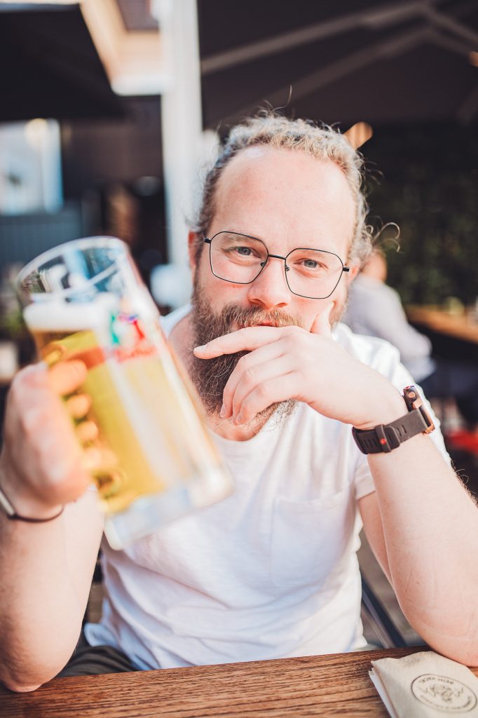 Person hält ein Glas Rothaus Bier auf der Restaurantterrasse