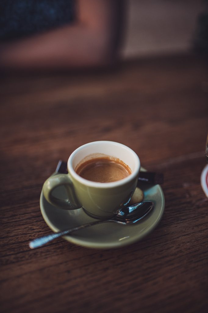 Kleine grüne Espressotasse mit Löffel auf Holztisch