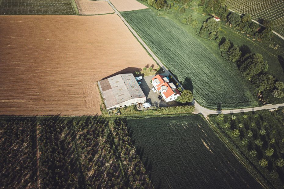 Drohnenaufnahme des Weinguts Holzwarth mit Hofgebäuden, Camper und umliegenden Feldern.