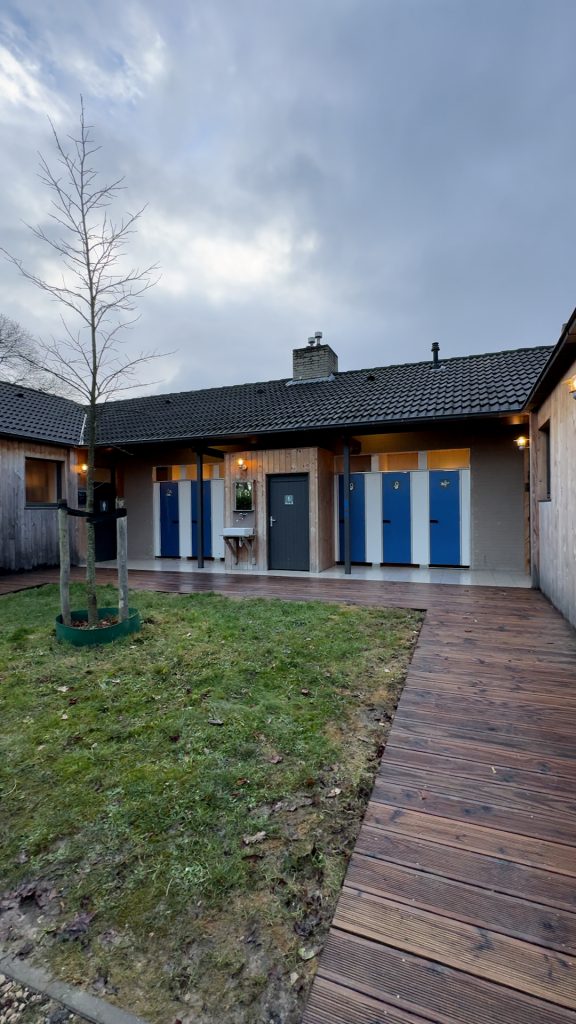 Außenansicht des Sanitärgebäudes mit blauen Türen im CityKamp Valkenburg im Winter