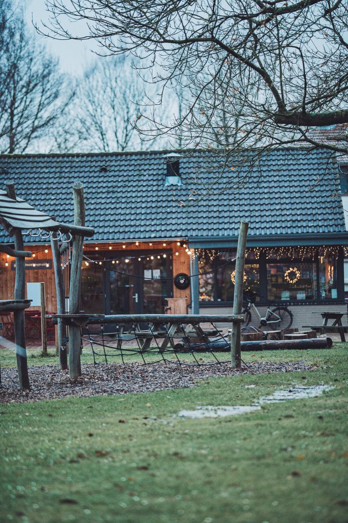 Spielplatz mit Holzelementen und Lichterkette vor dem Gebäude des CityKamp Valkenburg im Winter
