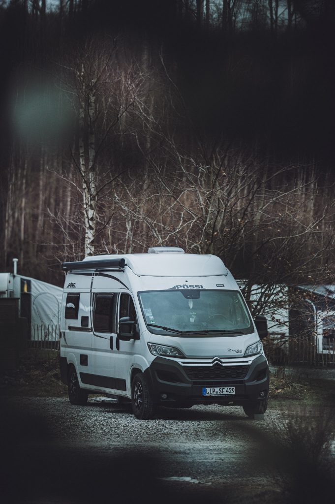Weißer Kastenwagen Camper auf geschottertem Stellplatz im Harz Camp Goslar vor kahlen Bäumen im Winter