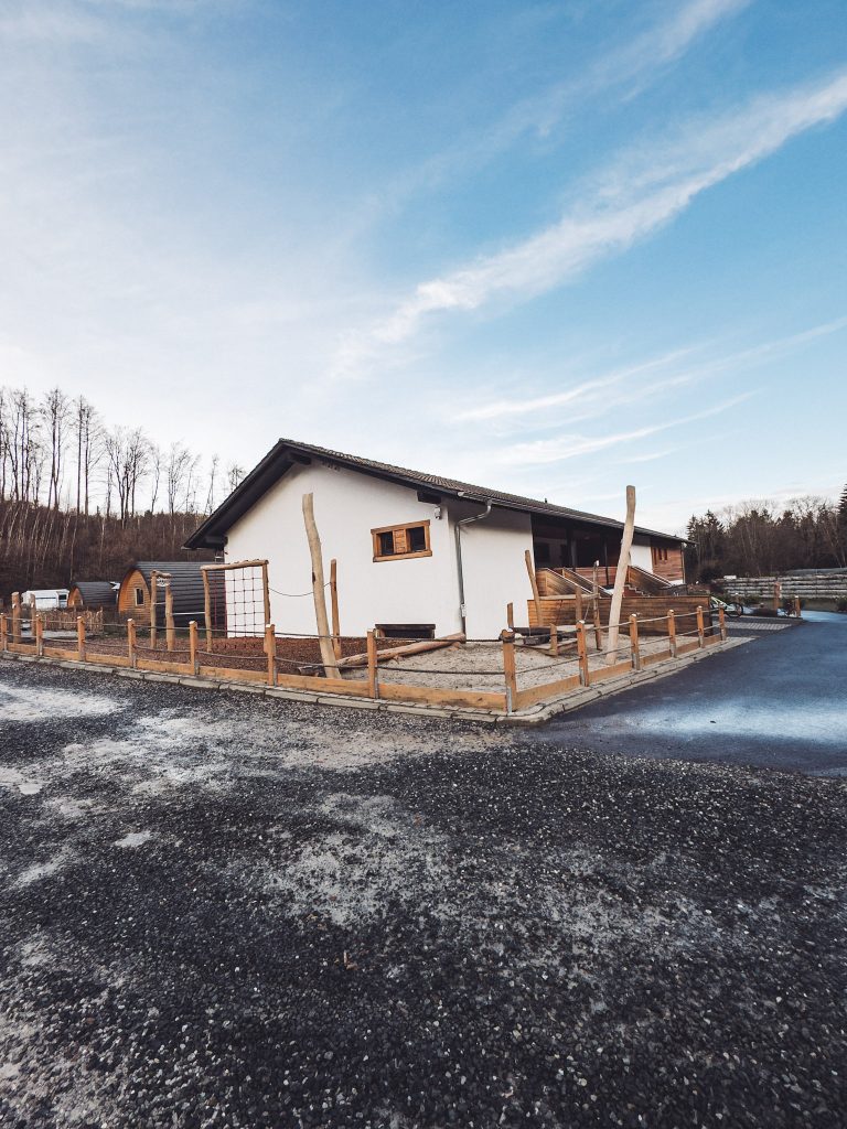 Modernes Sanitärgebäude im Harz Camp Goslar mit weißer Fassade, Holzelementen und umlaufenden Wegen