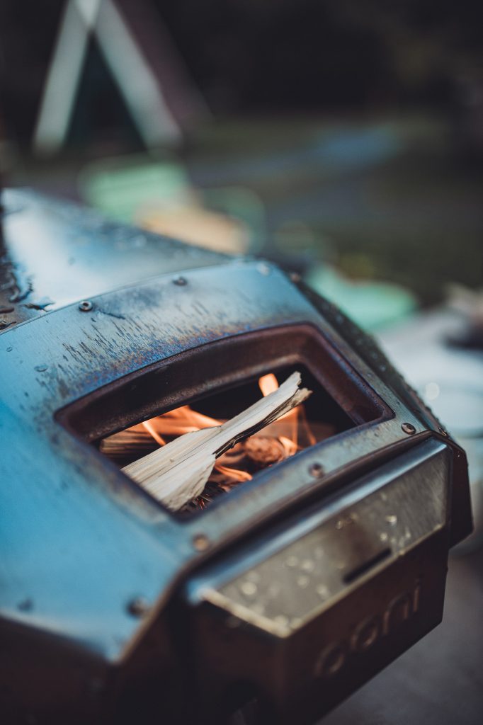 Nahaufnahme eines Pizzaofens mit brennendem Holz im Inneren und Wassertropfen auf der Metalloberfläche
