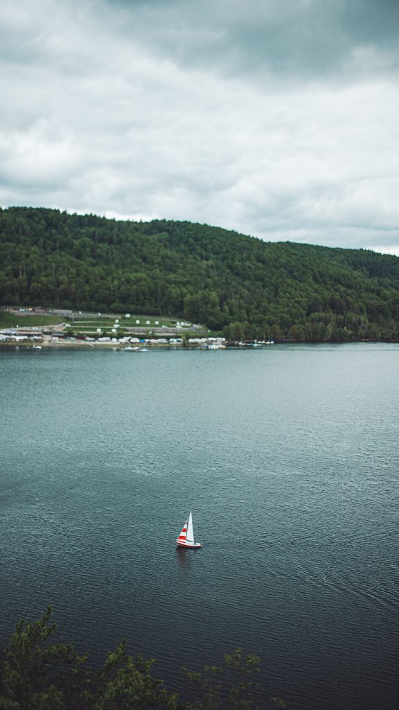 Segelboot auf dem Edersee vor bewaldeten Hügeln im Nationalpark Kellerwald-Edersee