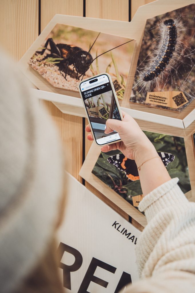 Besucherin scannt QR-Code an interaktivem Klima-Exponat