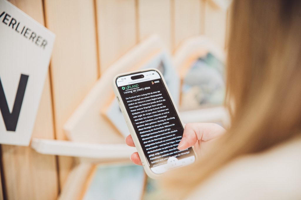 Smartphone zeigt Hintergrundinformationen zu einem Klima-Exponat