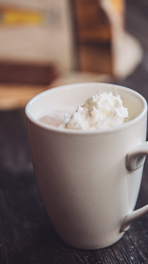 Weiße Tasse mit heißer Schokolade und Sahne auf einem Tisch in Valkenburg