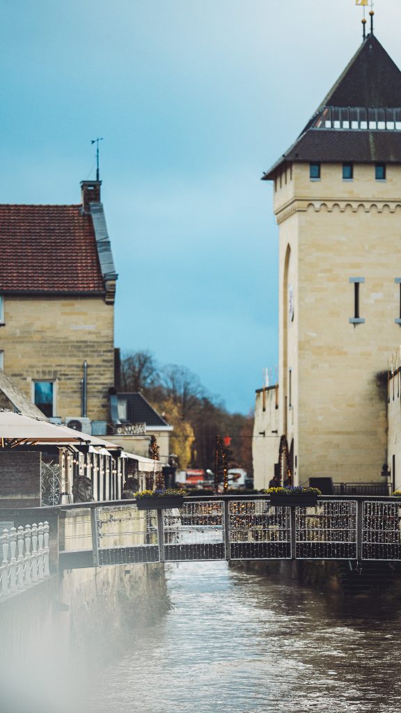 Flussufer in Valkenburg mit historischen Gebäuden und dekorierter Brücke im winterlichen Ambiente