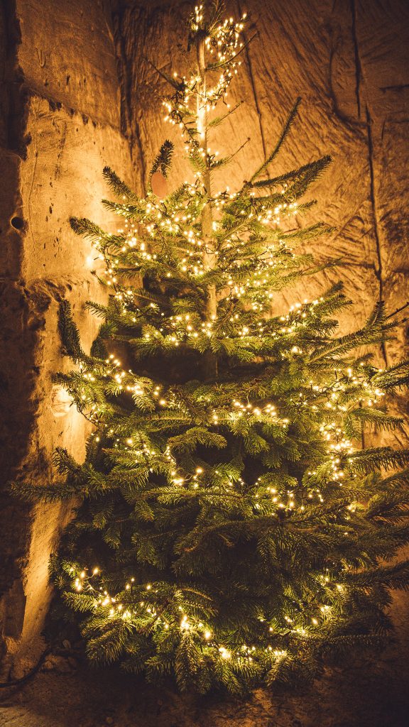 Weihnachtsbaum mit warmen Lichterketten in einer Höhle in Valkenburg