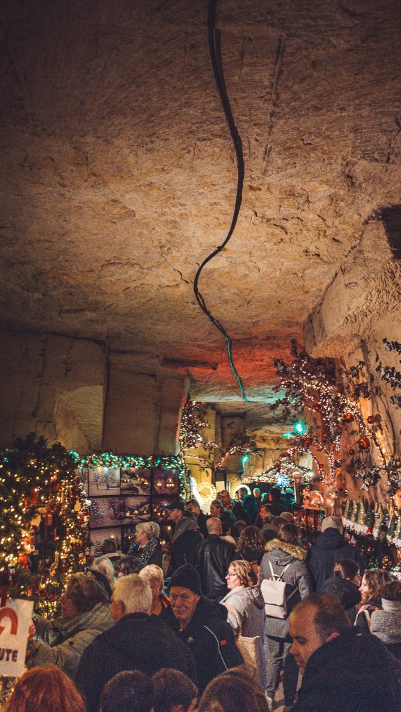 Menschenmenge und dekorierte Stände im unterirdischen Weihnachtsmarkt in Valkenburg