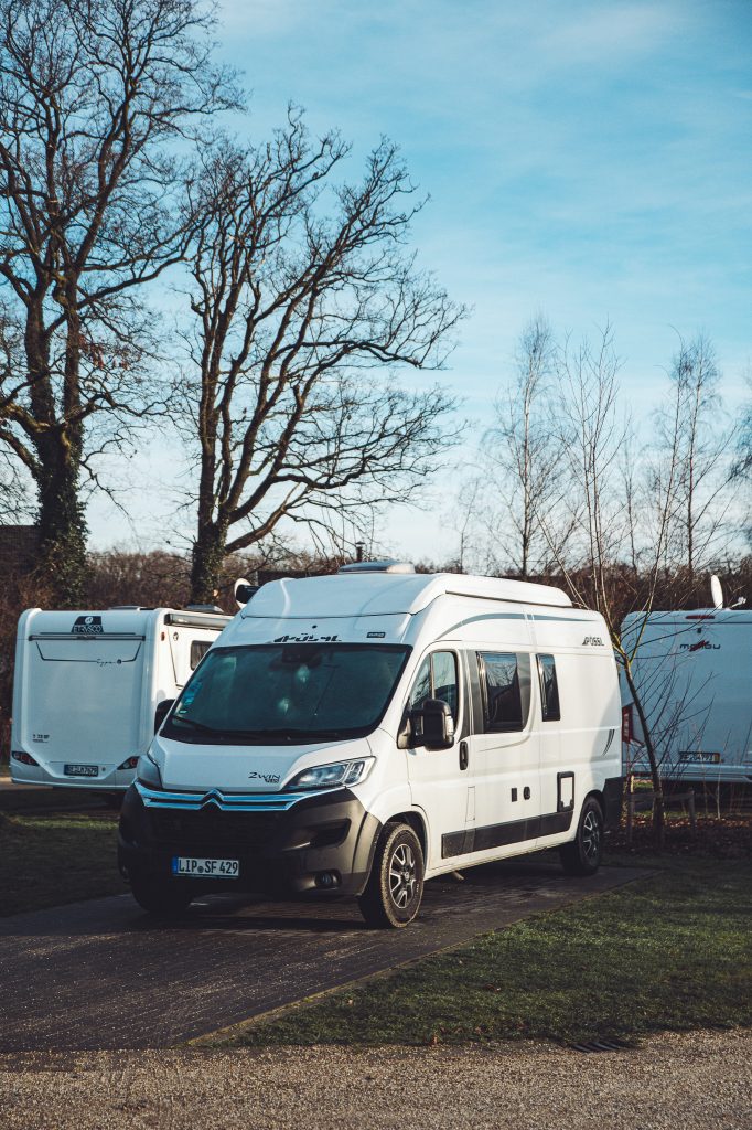 Weißer Campervan auf einem Stellplatz zwischen weiteren Wohnmobilen auf dem Camping Vreehorst