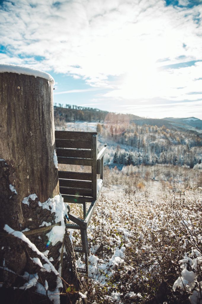 Hochsitz am Hang mit Blick über verschneite Landschaft und Wintersonne