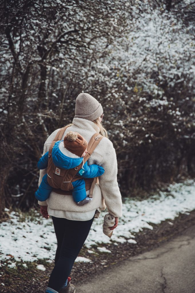 Person mit Baby in der Trage auf verschneitem Waldweg bei Olsberg