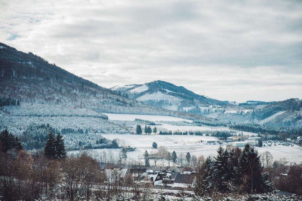 Weitblick über verschneite Landschaft mit Bergen, Wald und Dorf im Sauerland