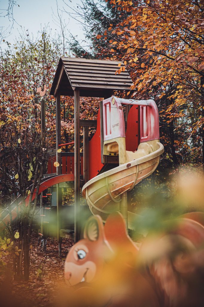 Spielplatz mit Rutsche und Kletterturm zwischen herbstlichen Bäumen am Camping des Charmilles in Belgien