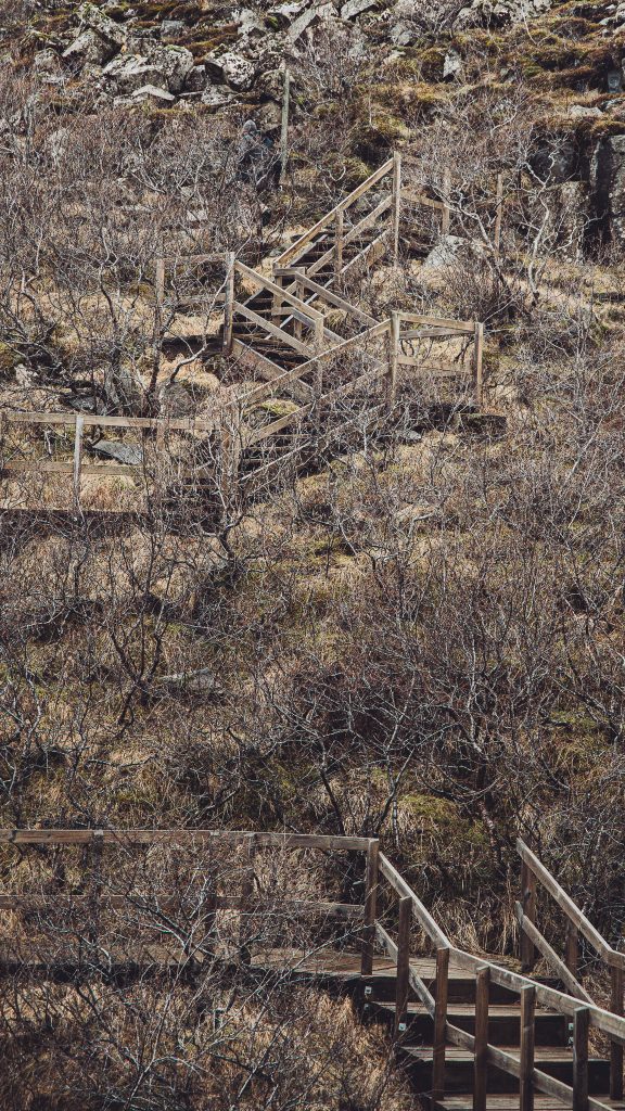 Holztreppen und Geländer auf einem Wanderweg in der kargen Landschaft Islands